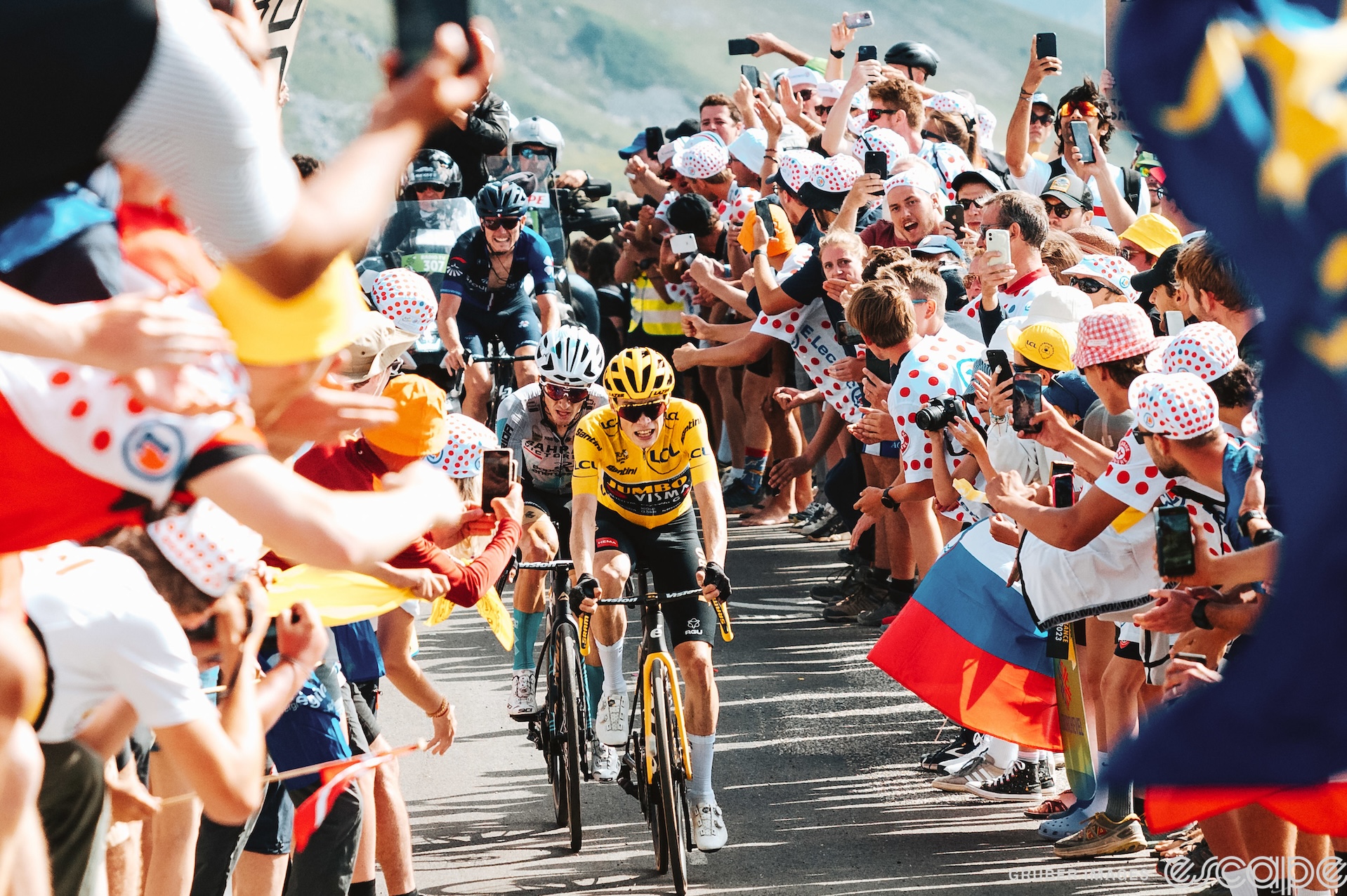 Jonas Vingegaard climbs the Col de la Loze on stage 17 of the 2023 Tour de France. He has Pello Bilbao behind him with David Gaudu a few meters behind, and they are surrounded by masses of flag-waving fans.