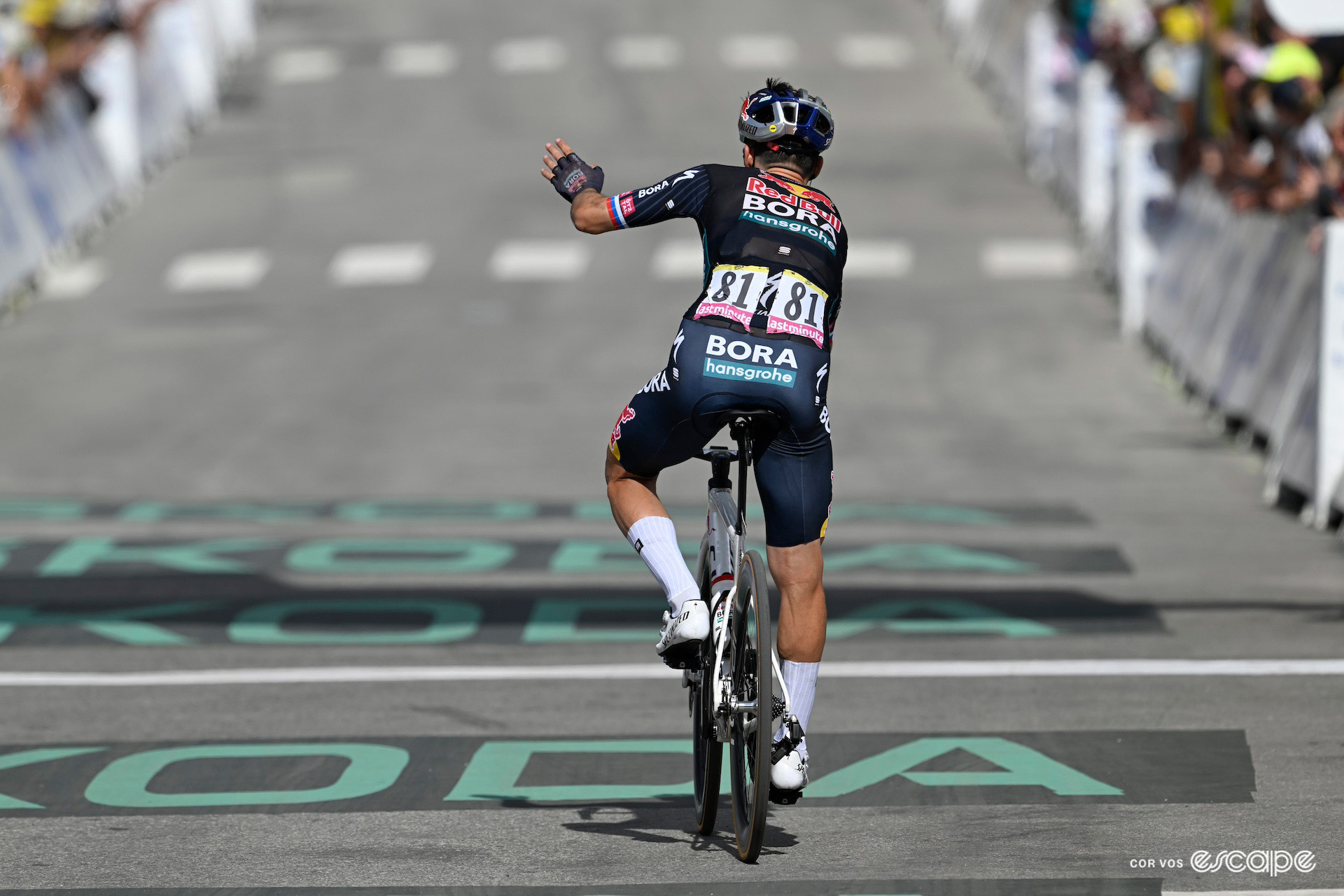 Primož Roglič crosses the finish line with a wave at the end of stage 4 of the 2024 Tour de France.