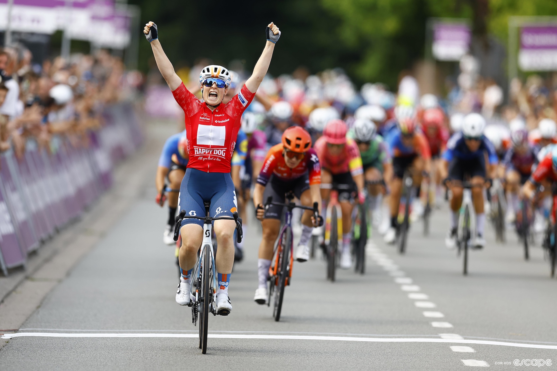 Charlotte Kool raises her arms in victory crossing the finish line on her bike