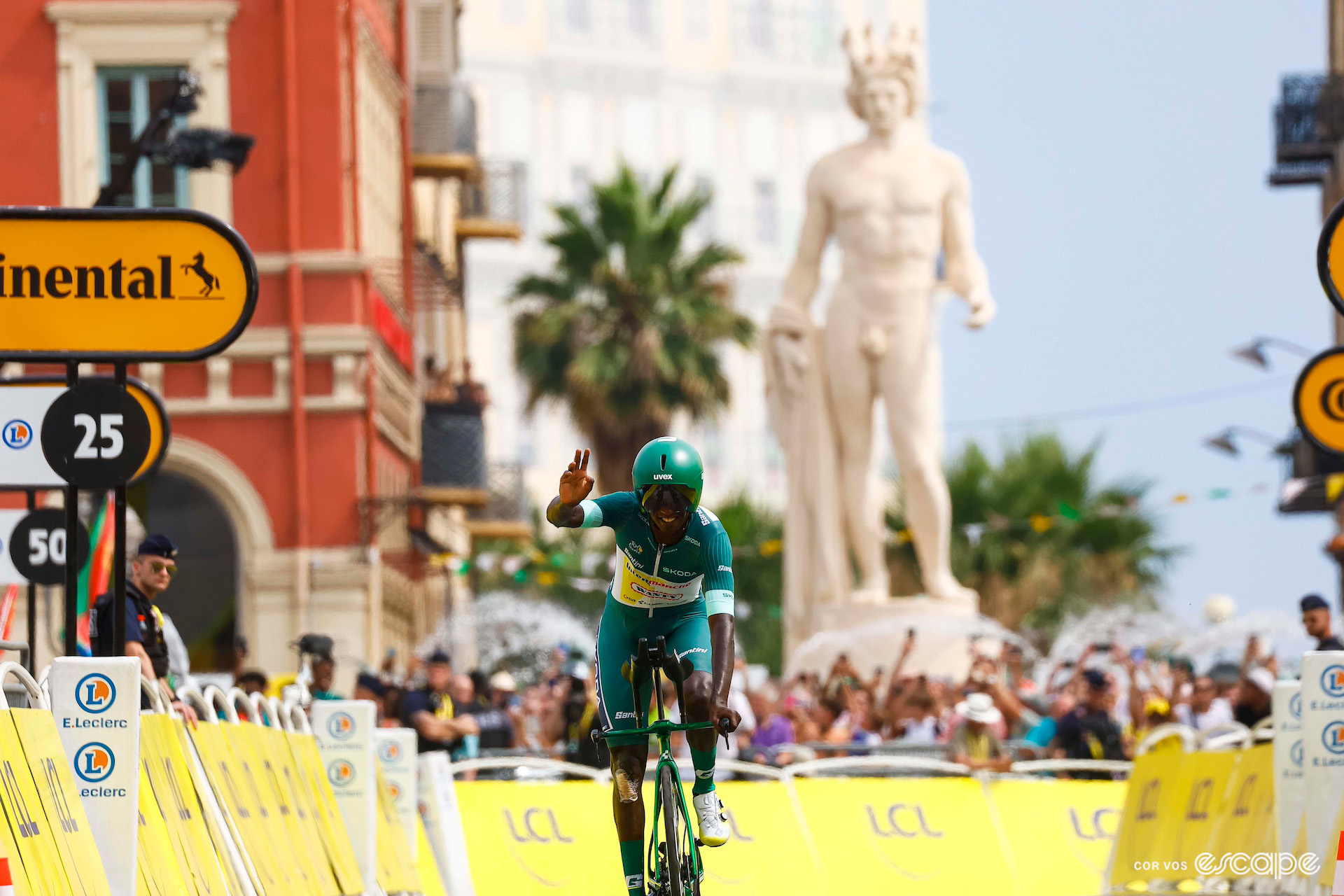 Biniam Girmay waves to the crowds as he crosses the line of the stage 21 time trial to finish the 2024 Tour de France.