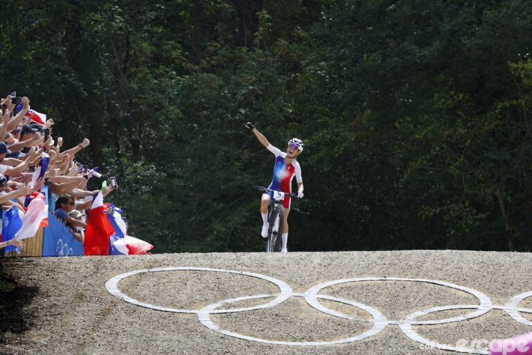 Pauline Ferrand-Prévot waves to the crowd as she crests the final roller on her way to a win at the Paris Olympics XCO.