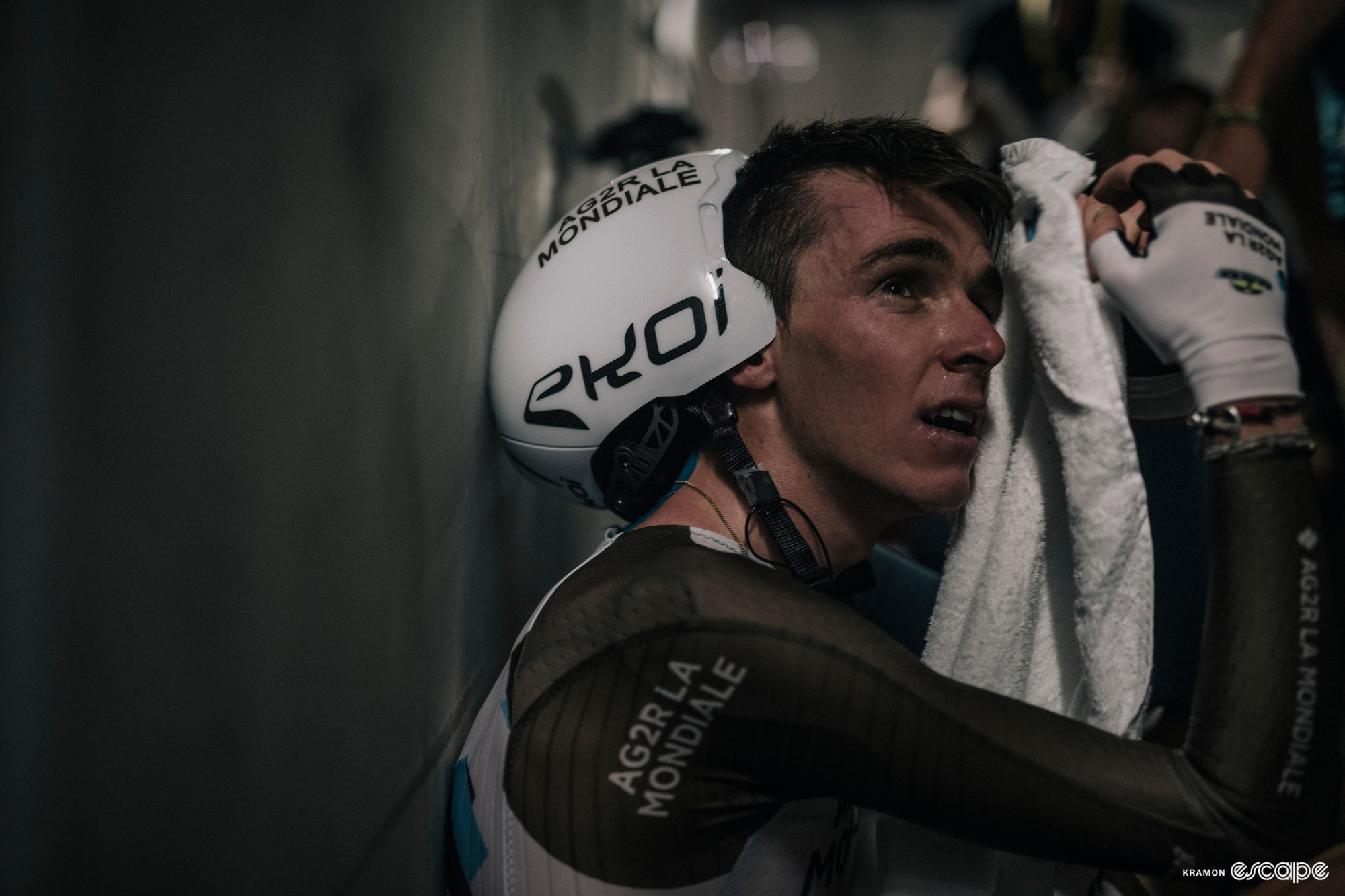 An exhausted Romain Bardet towels himself down, crouched against a wall, after the stage 20 time trial at the 2017 Tour de France.