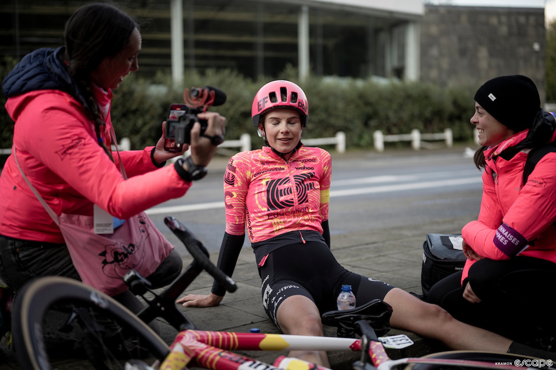 Kim sits on the ground after a race, flanked by team staff.