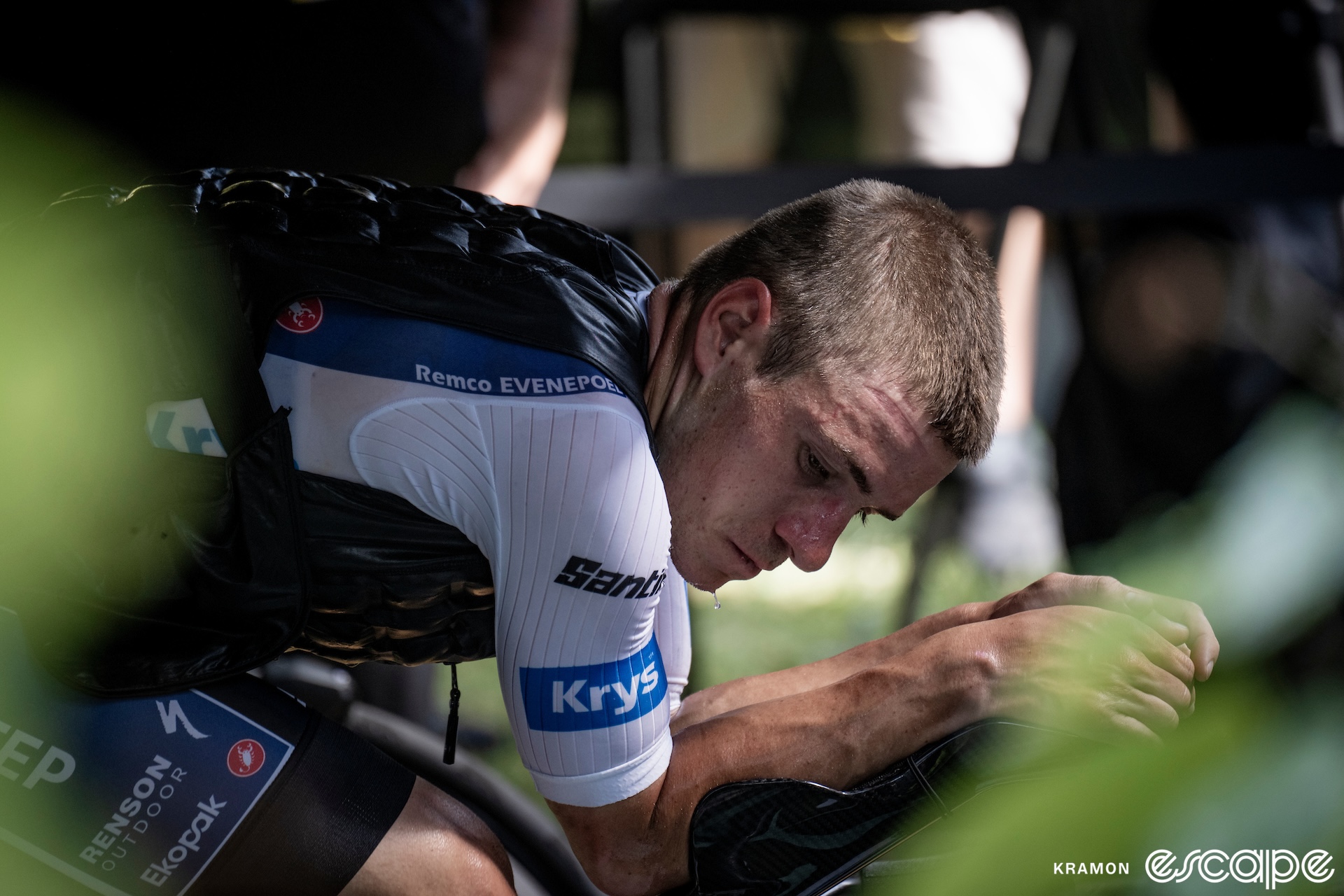 Remco Evenepoel looks slightly to his right as he warms up on a time trial bike. Sweat drips from his chin as he has a pensive expression.