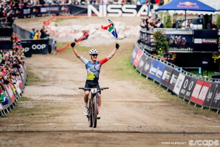 Alan Hatherly waves a South African flag as he comes to the line alone to win his first ever World Cup XCO at Les Gets, France.