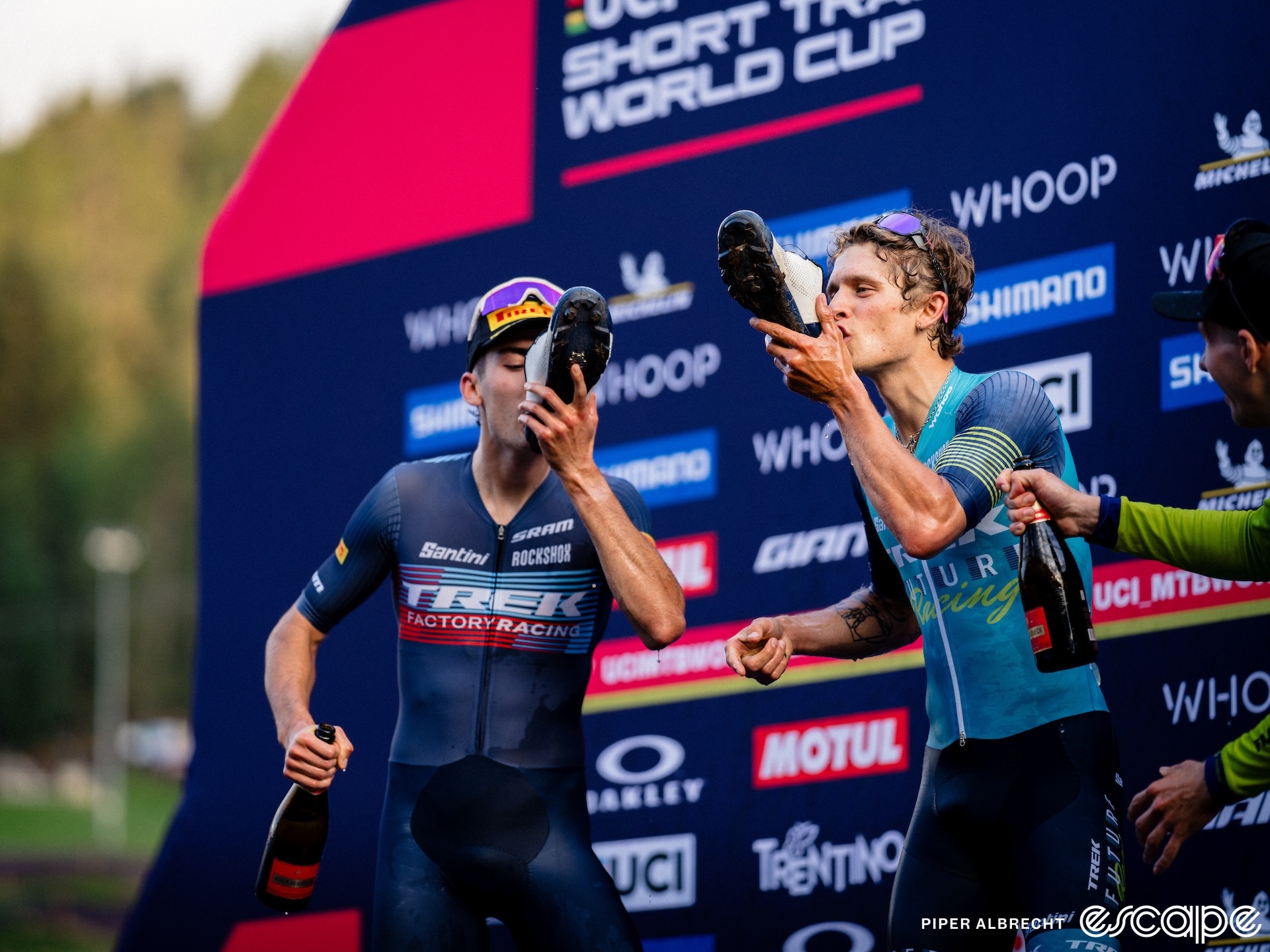 Riley Amos and Bjorn Riley drink champagne out of their shoes on the podium of a World Cup race. 