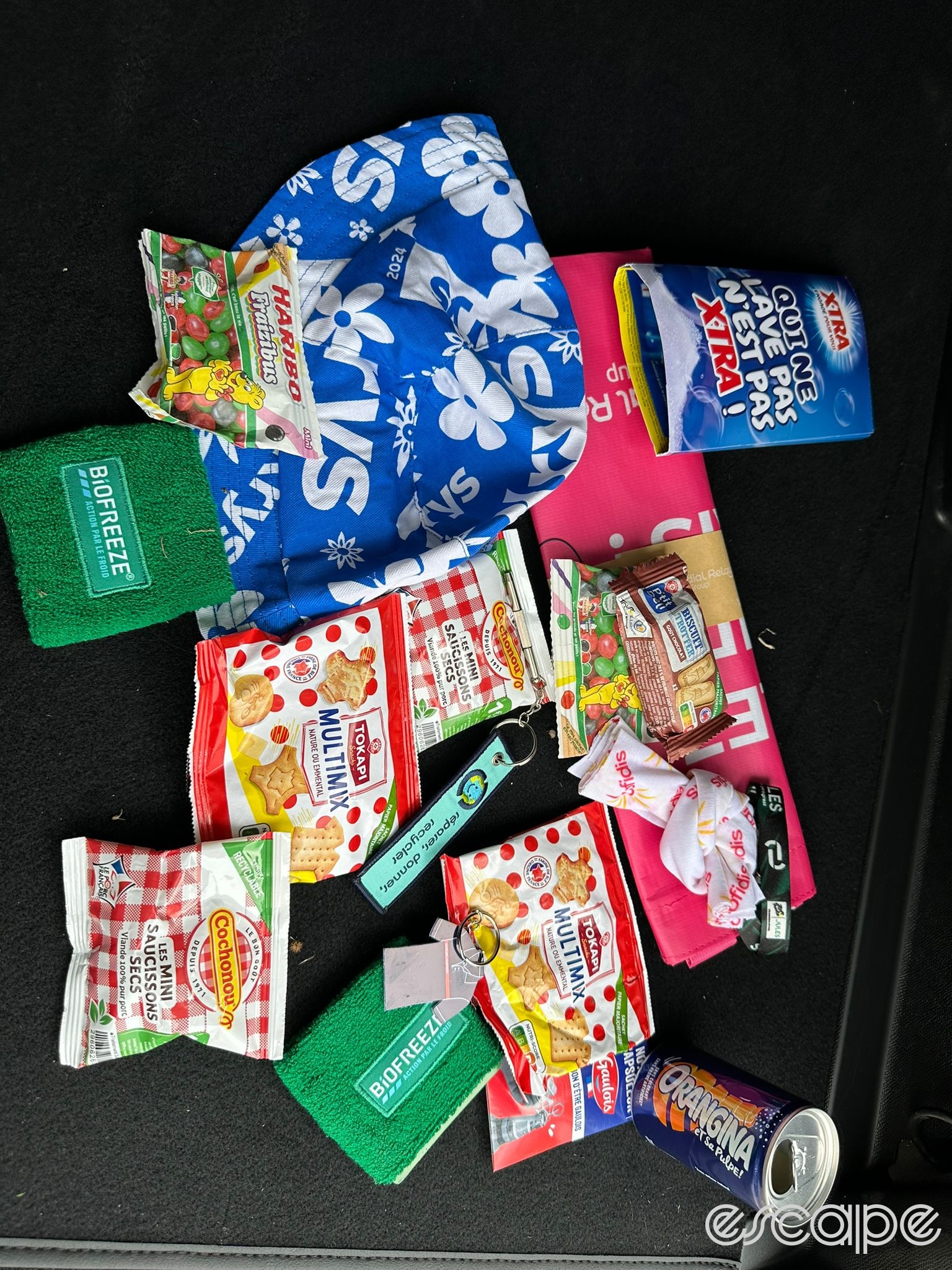 A selection of goodies thrown from the publicity caravan, including numerous foodstuffs, a can of Orangina, and a Krys cycling cap.