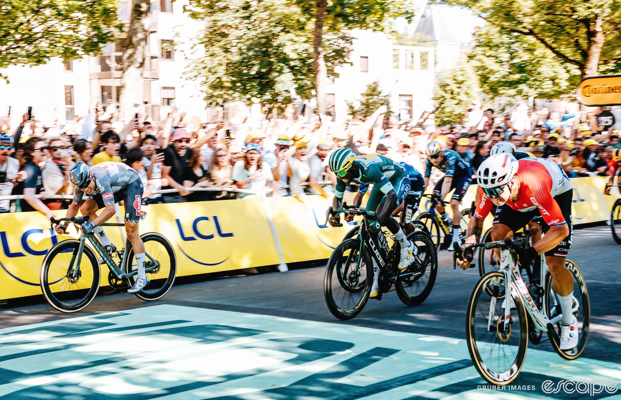 Jasper Philipsen, Biniam Girmay, and Dylan Groenewegen sprint for the win on stage 6. Philipsen, far left, is looking over at his rivals as they approach the line.