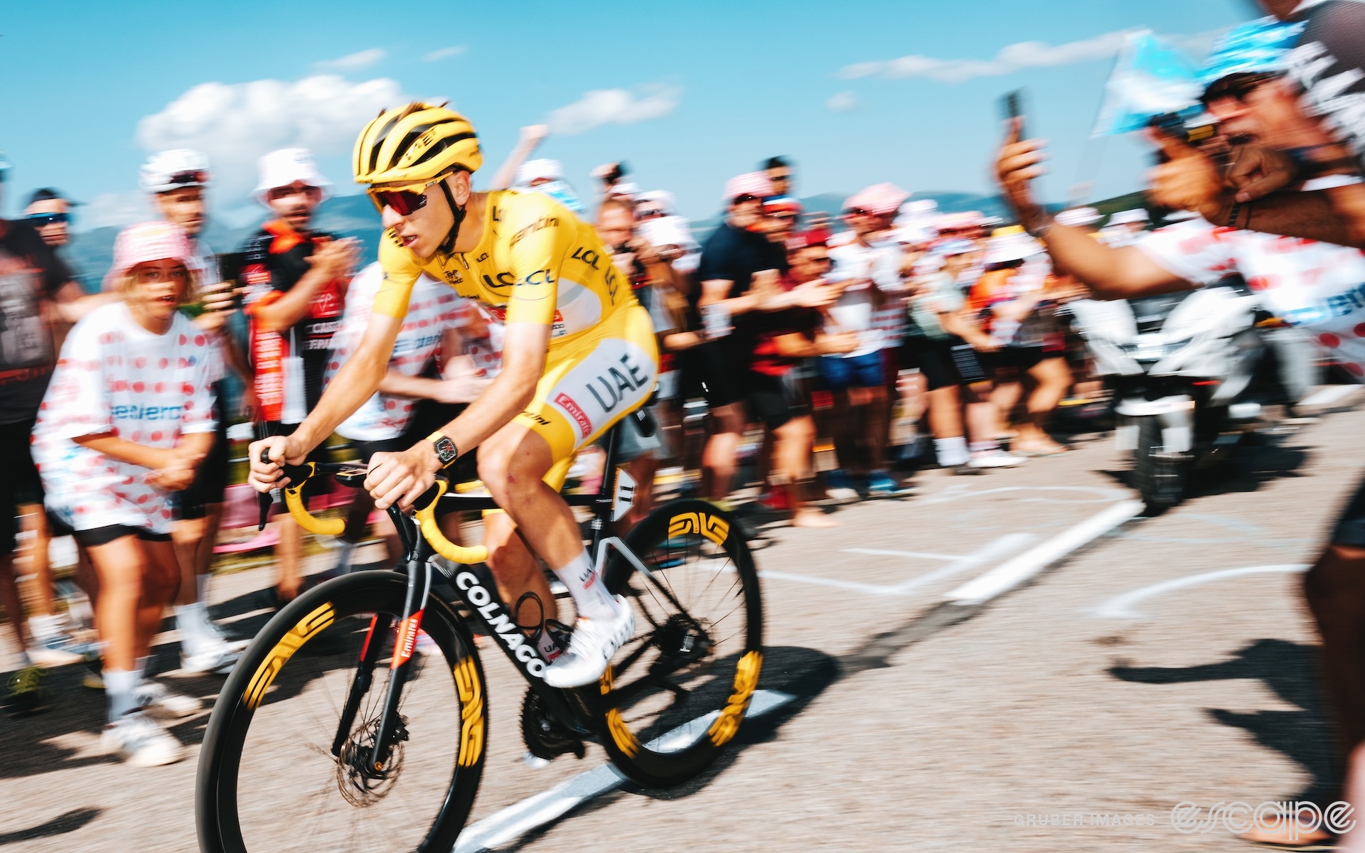 Tadej Pogačar climbs Plateau de Beille in the 2024 Tour de France. He's captured in a speed blur as if to accentuate his rapid ascent.