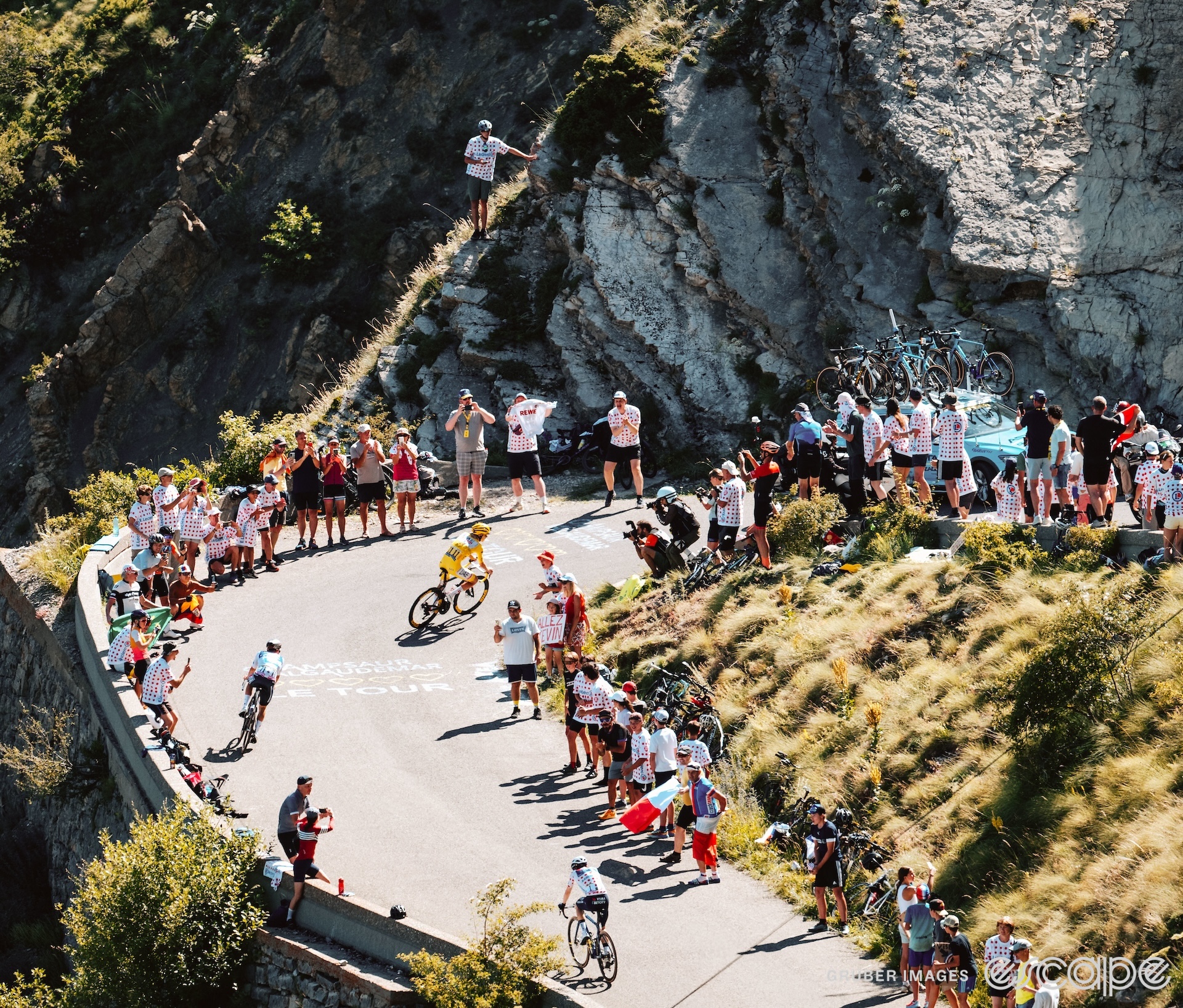 Tadej Pogačar attacks up a hill on stage 17 of the 2024 Tour de France. Rounding a switchback, he has a small gap to Remco Evenepoel, with Jonas Vingegaard trailing slightly farther behind.