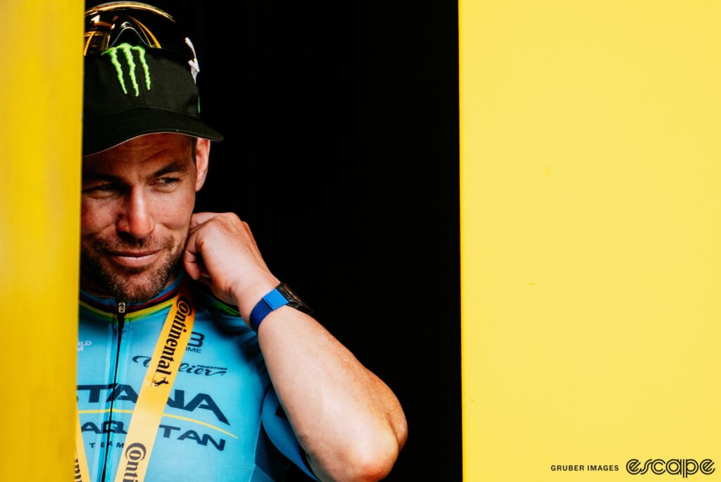 Mark Cavendish casts a sideways glance as he adjusts the winners medal around his neck on the podium of the Tour de France.
