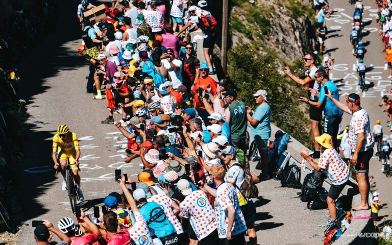 Tadej Pogačar rides alone on stage 17 of the 2024 Tour de France, surrounded by fans on a climb.