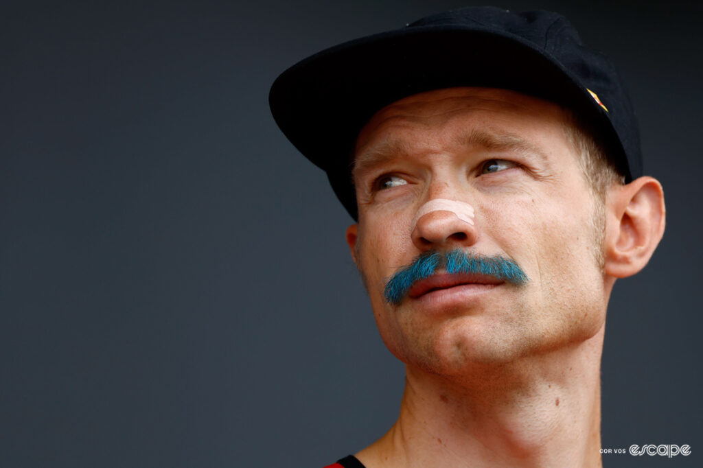 Magnus Cort wearing a cap and a freshly dyed blue moustache on stage 15 of the 2024 Tour de France.