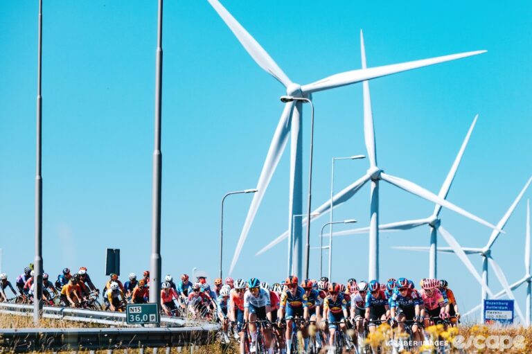 Riders race past wind turbines on stage 1 of the 2024 Tour de France Femmes.