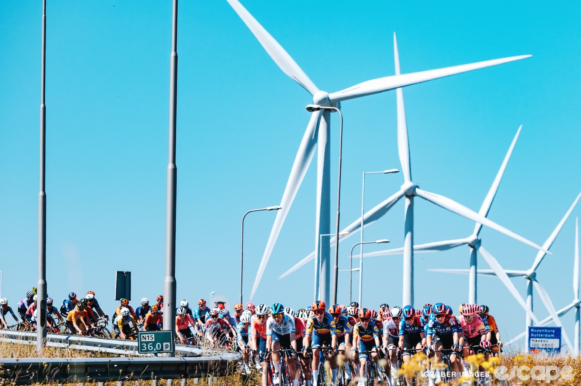 Renners passeren windturbines in fase 1 van de Tour de France Femmes 2024.